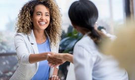 Attractive young mixed race businesswoman shakes hands with a female colleague during a business meeting.